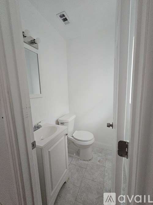 A bathroom with a toilet, sink, and mirror.