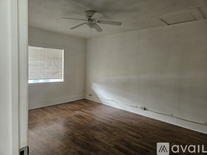A room with a ceiling fan and wooden flooring.