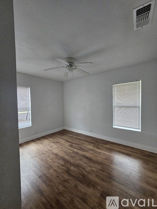 A room with a ceiling fan and wooden flooring.