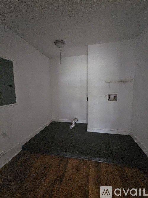 A room with a wooden floor and a white wall.