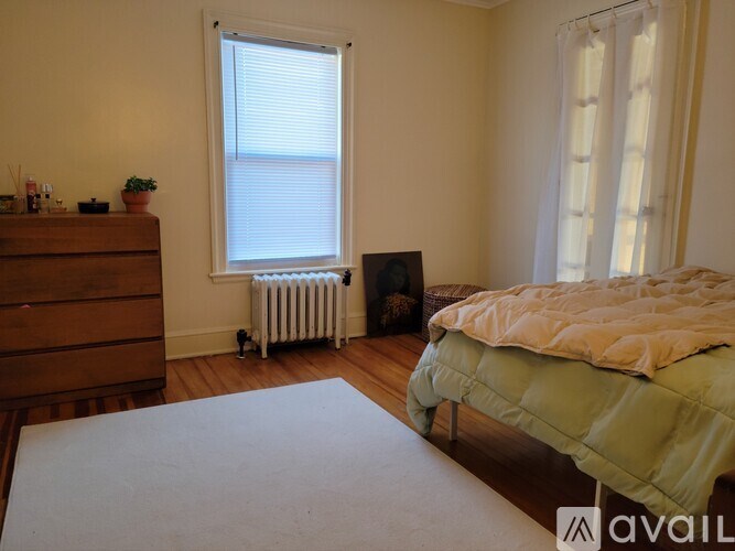 A bedroom with a bed, dresser, and window.