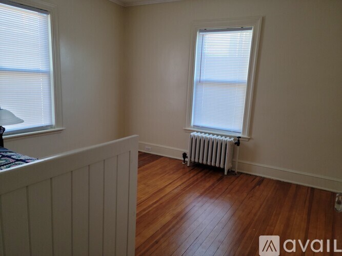 A room with wooden floors and a window with blinds.