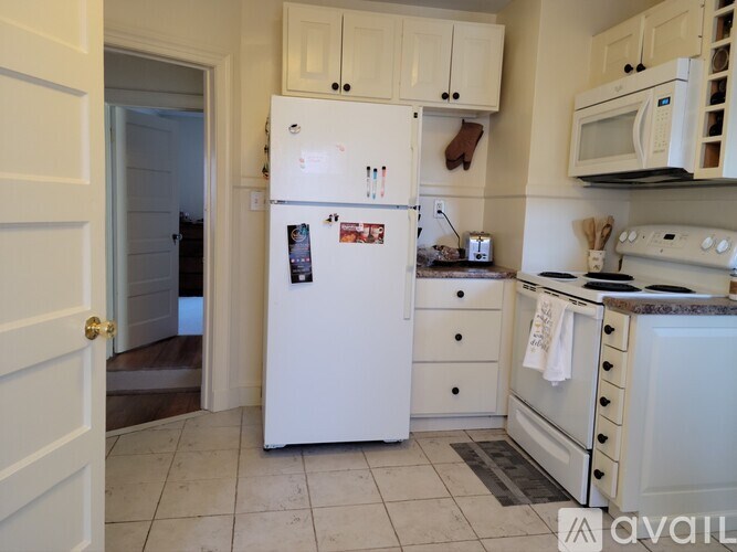 A white refrigerator with a few magnets and papers on it is in a kitchen.