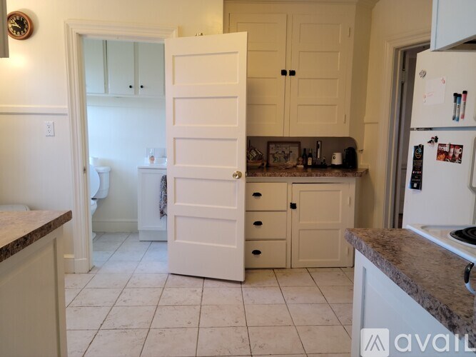 A kitchen with white cabinets and a refrigerator.