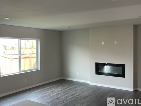 A spacious living room with a fireplace and a large window.