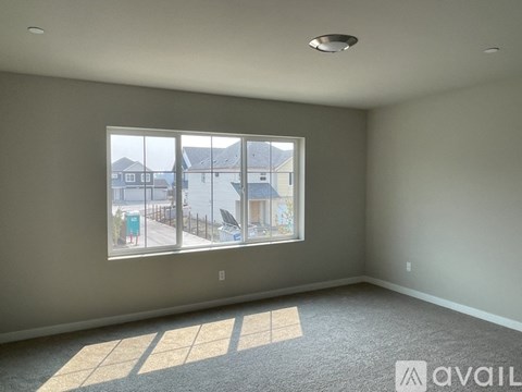 A room with a large window overlooking a street with houses.
