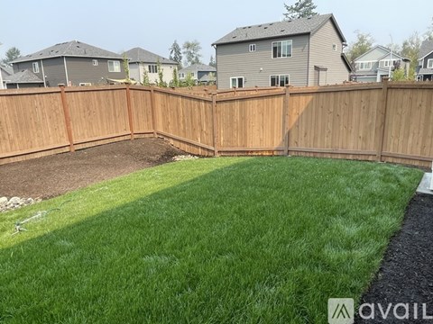 A backyard with a wooden fence and a green lawn.