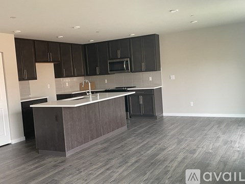 A modern kitchen with dark brown cabinets and a central island.