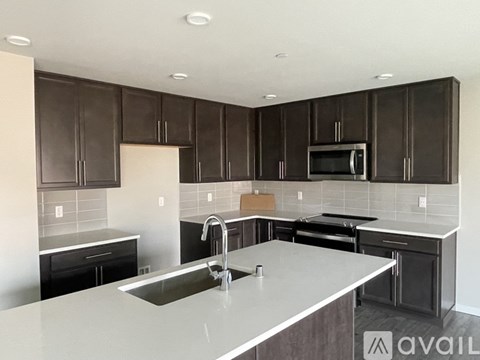 A kitchen with dark brown cabinets and a white countertop.