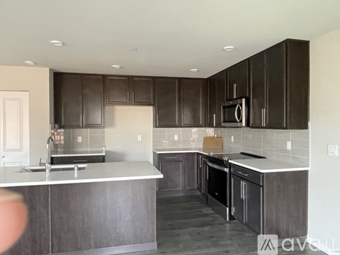 A kitchen with dark brown cabinets and a white countertop.