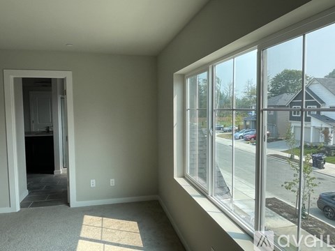 A room with a large window and a door leading to another room.