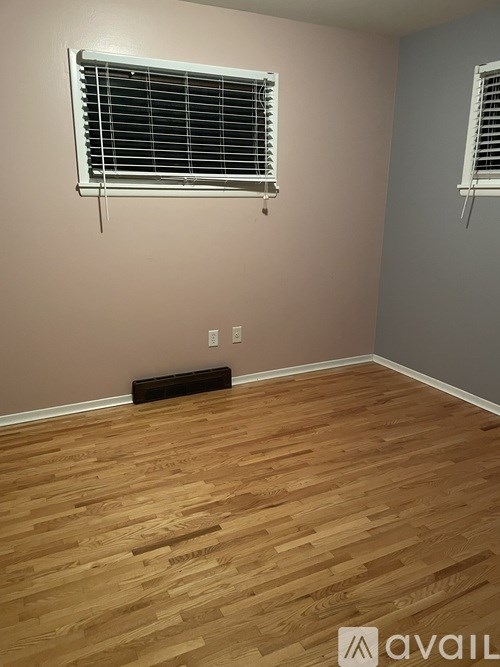 A room with wooden flooring and a window with blinds.