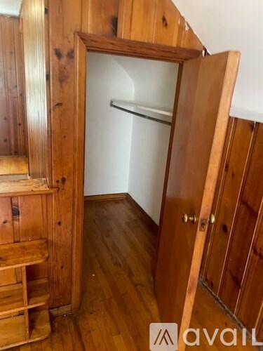 A wooden staircase with a glass door leading to a white wall.