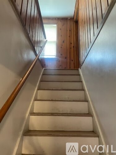 A wooden staircase with a white riser and a brown handrail.