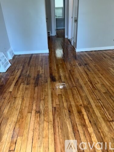 A room with wooden flooring and a white wall.