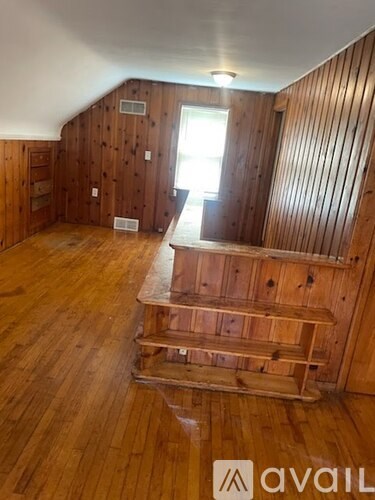 A room with wooden walls and floors and a window.