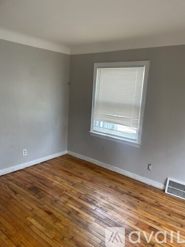 A room with wooden flooring and a window with blinds.