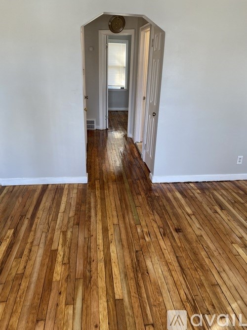 A hallway with wooden floors and white walls.