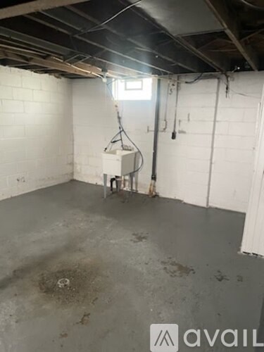 A dirty basement with a window and a white door.