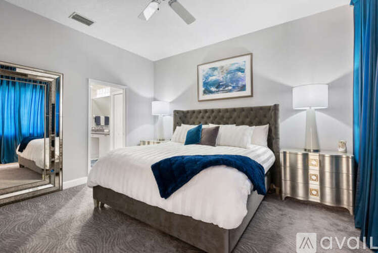 A bedroom with a large bed and a painting on the wall.