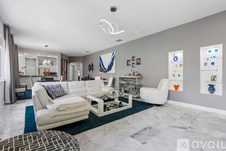 A modern living room with white furniture and a blue rug.