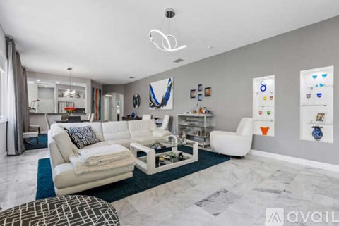 A modern living room with white furniture and a blue rug.