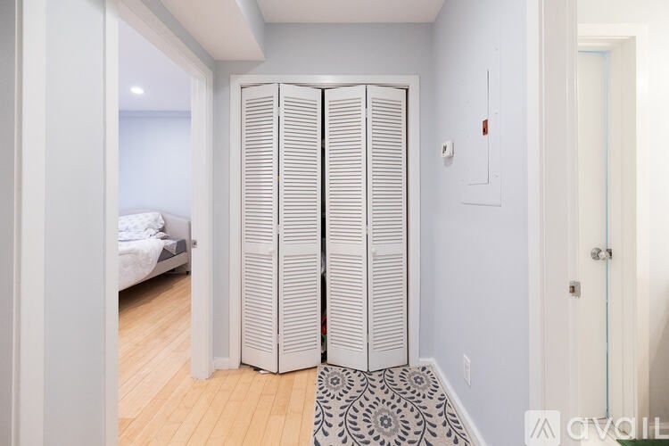 A room with a white door and a black and white patterned rug.