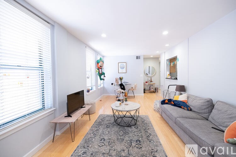 A living room with a grey couch, a black coffee table, and a television on a stand.