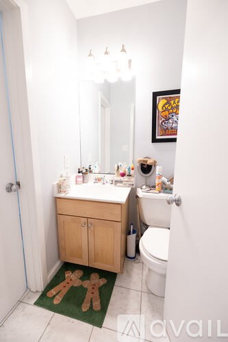 A bathroom with a toilet, sink, and a green rug on the floor.