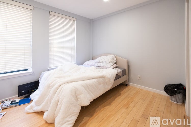 A bedroom with a bed covered in a white comforter and a basket on the floor.