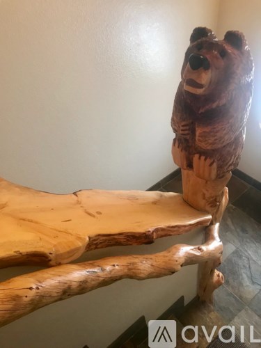 A wooden bear statue is sitting on a log.