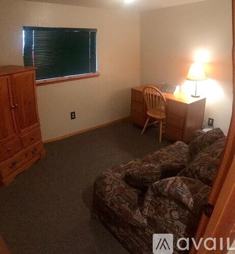 A room with a couch, chair, and lamp.