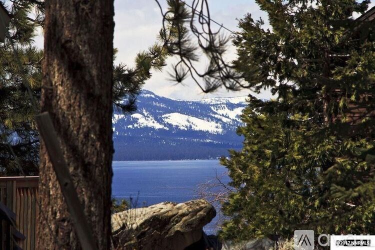 A view of a mountain range with a lake in the foreground and trees in the foreground.