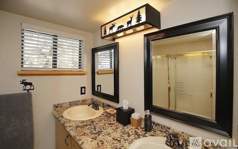 A bathroom with a sink, mirror, and a framed picture of a deer.
