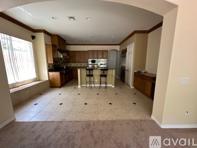 A spacious kitchen and living room with a bar stool and a refrigerator.