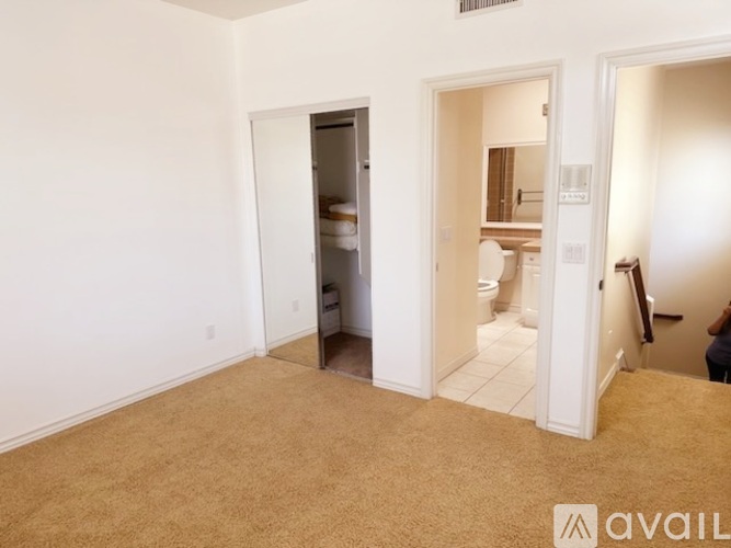 A carpeted room with a doorway leading to another room.