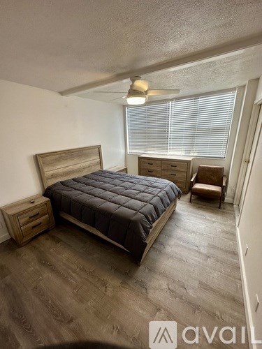 A bedroom with a bed, chair, and drawers.