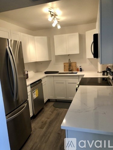 A kitchen with a stainless steel refrigerator and white cabinets.