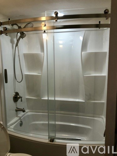 A glass shower door with a silver handle and a glass shelf.