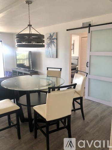 A modern dining room with a glass table and chairs.