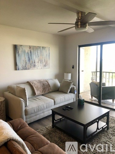 A living room with a white couch and a painting on the wall.