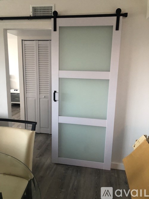 A glass door with a white frame and a black handle.