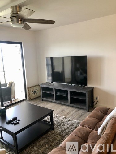 A living room with a flat screen TV and a ceiling fan.