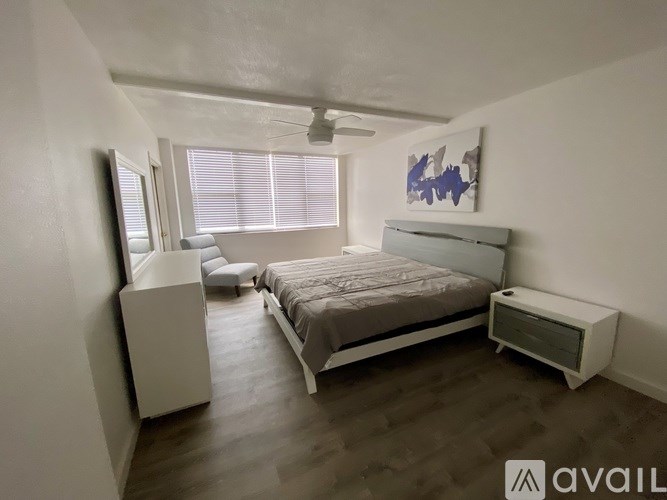 A bedroom with a bed, nightstand, and a window with blinds.