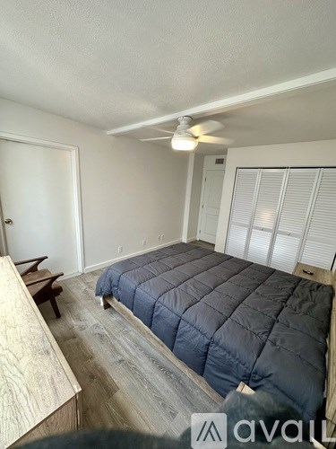 A bedroom with a bed, a bench, and a window with blinds.