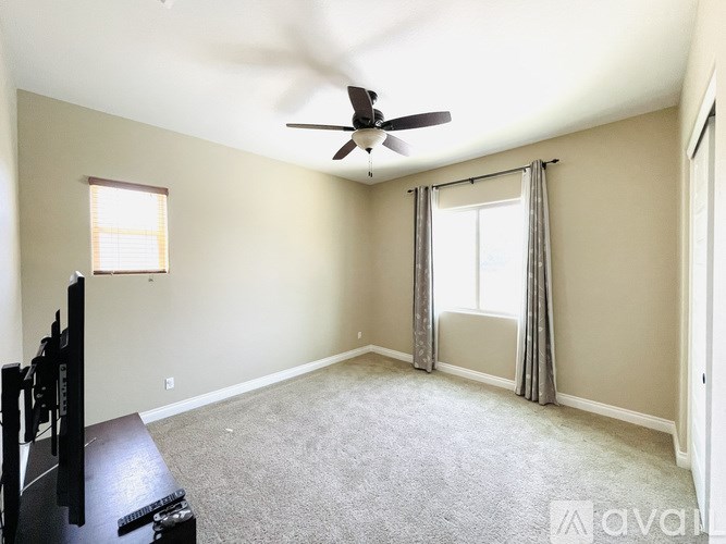 A room with a ceiling fan and a window with curtains.