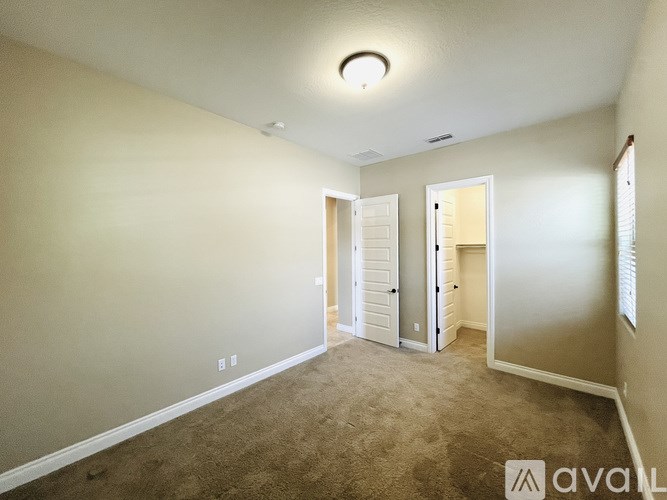 A carpeted room with a doorway leading to another room.