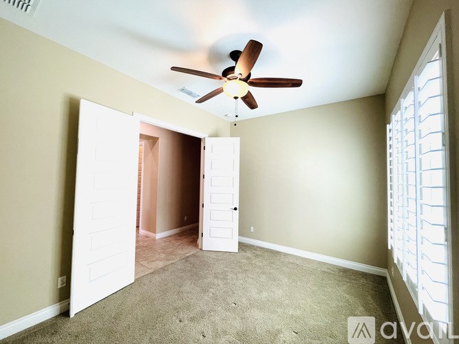 A room with a ceiling fan and a window with blinds.