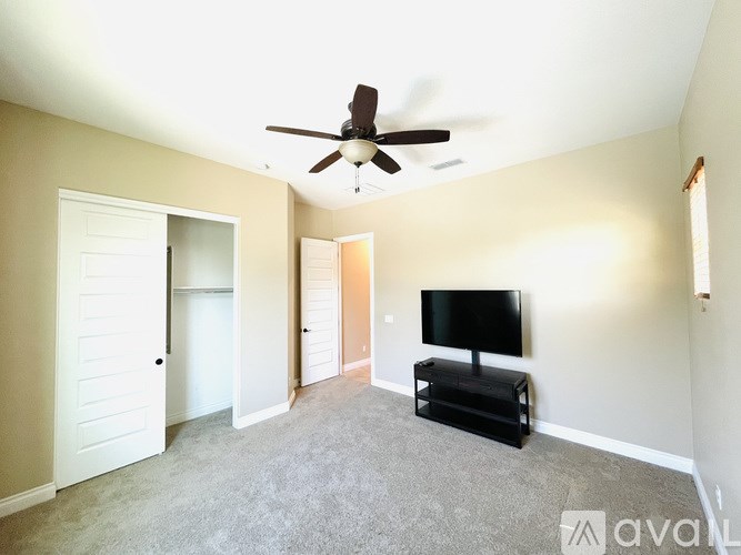 A living room with a television and a ceiling fan.