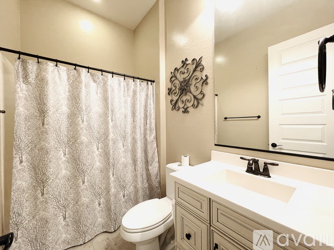 A bathroom with a white toilet, a sink, and a shower curtain.